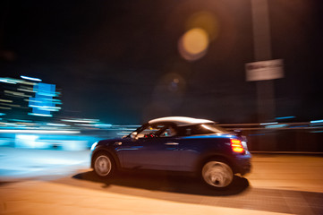 Fototapeta na wymiar Blue Mini S Coupé Car, Speeding Through The Night
