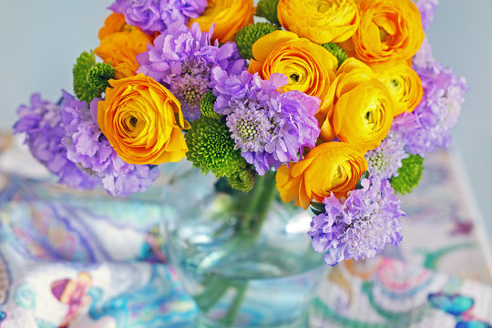 Beautiful bouquet of flowers.Yellow ranunculus flowers and scabious close-up in a glass vase on the table. 
