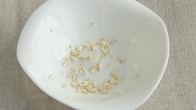 The oat flakes strew into the plate footage slow motion
