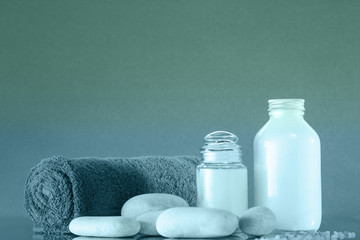 Spa. The towel is rolled up, white pebbles, two bottles of cream. Toned
