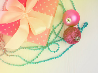 the gentle pink new Christmas gift with a nice ribbon, bowknot, white wood background, copy space for text, concept of the gift. holiday, gift, added a snow effect, with two Christmas ball. flatlay