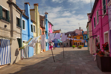 Fototapeta na wymiar The colorful architecture of the sunny Island of Burano, a tourist attraction near Venice, Italy, which shows the harmony, joyful approach and lifestyle