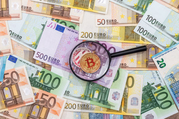 A man looks at bitcoin through a magnifying glass against the background of the euro