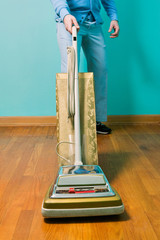 Man cleaning floor with vintage vacuum cleaner