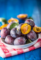 Plums. Fresh juicy plums in a bowl on a wooden or concrete board.