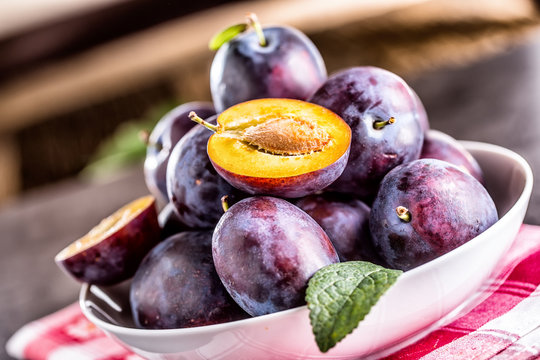 Plums. Fresh juicy plums in a bowl on a wooden or concrete board.