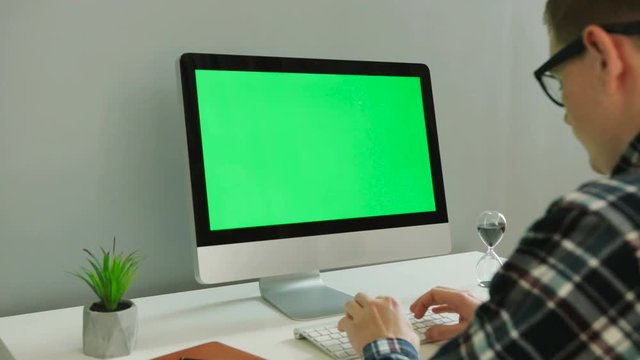 Close up shot of business man in the glasses using computer with green screen in the modern office. Chroma key.
