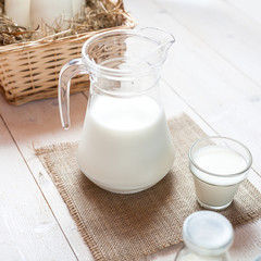 jug of milk and glasses of milk on a wooden rustic table.