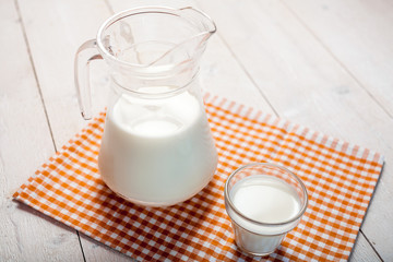 milk and glasses of milk on a wooden rustic table.