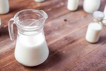 jug of milk and glasses of milk on a wooden rustic table.