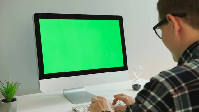 Portrait of business man with glasses using computer with green screen in the modern office. Chroma key.