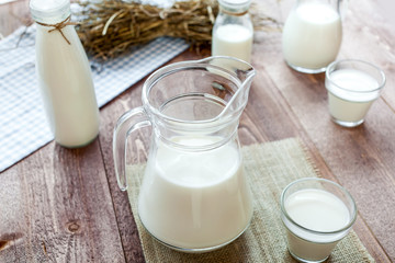 milk and glasses of milk on a wooden rustic table.