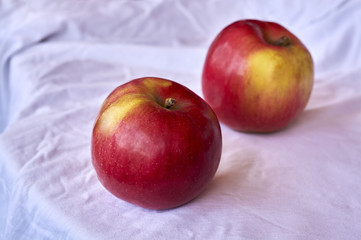 Two red apples placed on white cloth
