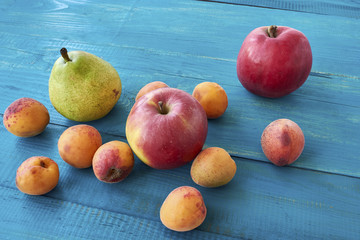 Ripe apricots, apples and pears on a blue wooden table