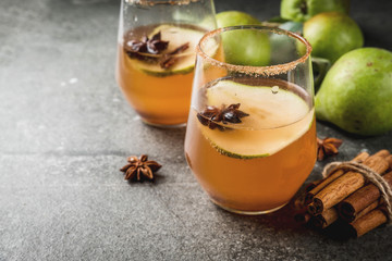 Autumn drinks. Mulled wine. Traditional autumn spicy cocktail with pear, cider and chocolate syrup, with cinnamon, anise, brown sugar. On black stone table. Copy space