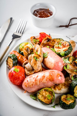 Barbecue. Assortment of various grilled meat sausages, with vegetables BBQ - mushrooms, tomatoes, zucchini, onions. On white marble table, on plate, with sauce. Copy space