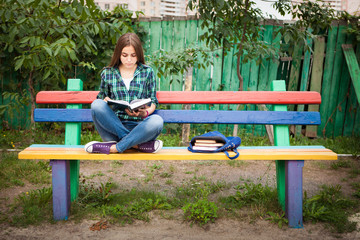 Beautiful teenage girl reading book outdoors
