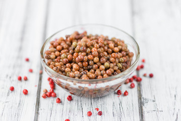 Portion of Pink Peppercorns (preserved) on wooden background, selective focus