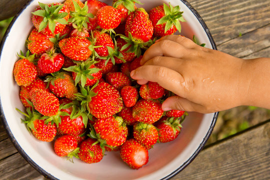 Baby hand taking strawberries from a plate