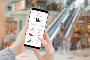 Woman buying heels online on smartphone in shopping mall