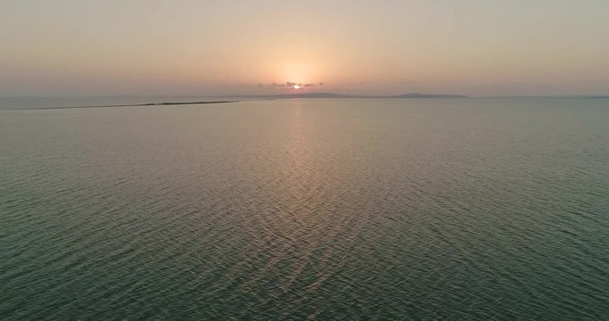 Aerial drone view of flock of birds flying away under the sea at the sunset. Flight with a flock of birds over the sea.