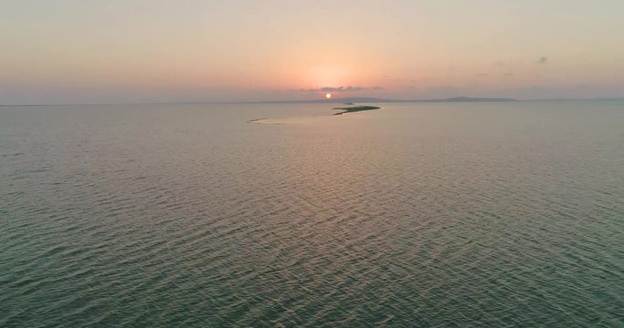 Aerial drone view of flock of birds flying away under the sea at the sunset.