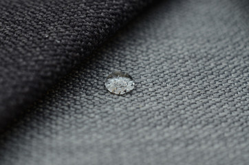 Close up water drop on grey gunny textile. Concept for easy clean, waterproof surfaces