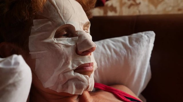 Spa therapy for an elderly woman who receives a face mask. 4k. Slow motion. Home facial care