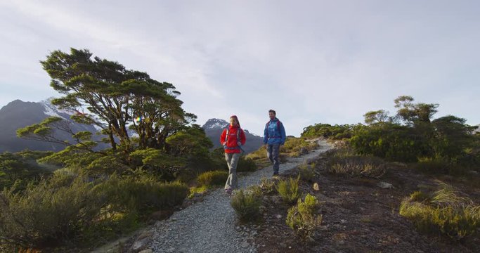 Hiking couple walking on trail at Routeburn Track during sunny day. Male and female hikers are tramping on Key Summit Track. travelling in Fiordland National Park in New Zealand.