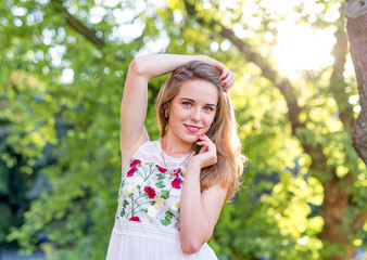 Beautiful girl posing in the street on the background of green trees