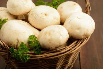 Mushrooms in basket with greens, close-up view