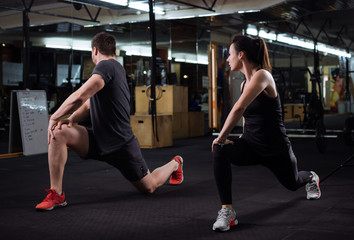 Fototapeta na wymiar Couple of man and woman doing sport exercises at the gym