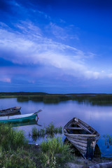 Obraz premium Scenic Destinations. Line of Boats on Water Placed in Belarussian National Park Braslav Lakes at Sunset during Summer Time.