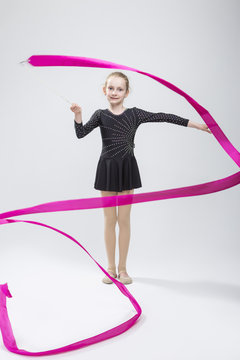 Portrait of Caucasian Female Rhythmic Gymnast In Professional Competitive Black Sparkling Starry Suit Doing Artistic Ribbon Spirals Exercises in Studio On White.