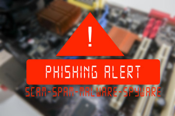 Blurred PCB Closeup of electronic circuit board with CPU processor with PHISHING ALERT words.