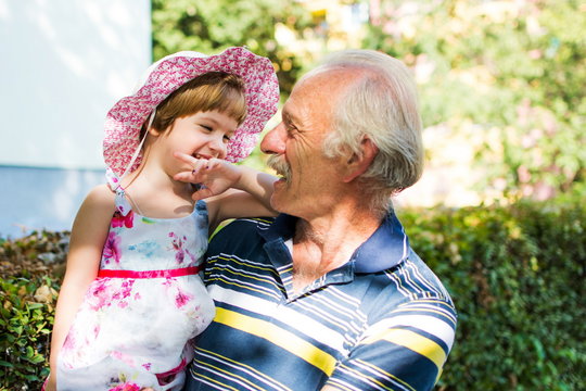 Grandpa and his granddaughter laughing outdoors