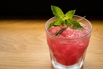 Pink cocktail with mint and rosemary garnish