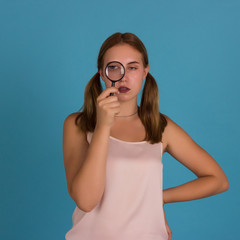 Young pretty girl with magnifier, studio  