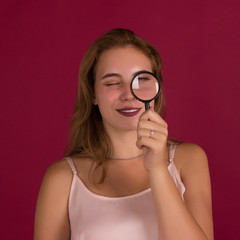 Young pretty girl with magnifier, studio  