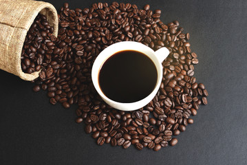 Cup of coffee with beans on black table