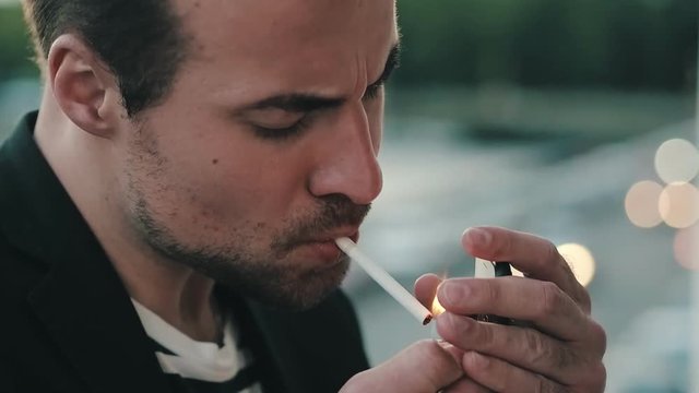 Handsome man takes a cigarette and light it up. Tired man smokes a cigarette