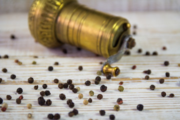 Vintage Turkish pepper mill with sprinkled peppers on a wooden background