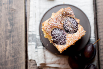 Homemade pie with plums on the wooden table background. Fruit autumn cake with cinnamon. Top view