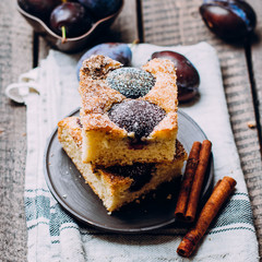 Homemade pie with plums on the wooden table background. Fruit autumn cake with cinnamon. 