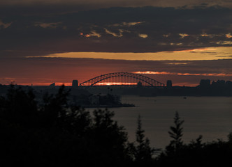 Obraz premium Sunset in the distance over Sydney Harbour Bridge and the city