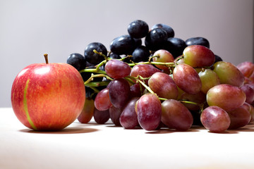 ripe red apple and grapes on grey background
