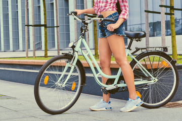 Woman's tan legs riding a bicycle over modern building background.