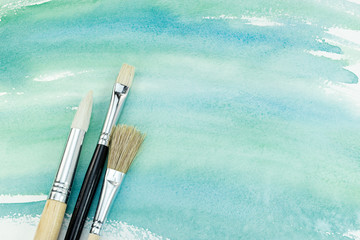 Obraz premium hand painted watercolor paper in green colors with paintbrushes