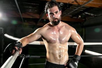Fototapeta na wymiar Handsome male MMA fighter posing portrait inside the ring looking strong and confident