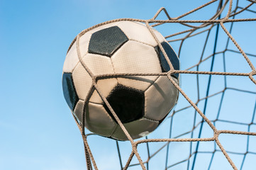 Soccer ball in the goal net with blue sky background